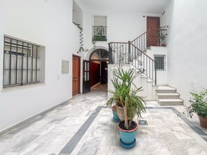 A clean, well-lit hallway with a marble floor, a staircase, and potted plants. - GuestReady - Atico Luna Puerto (El Puerto de Santa María)