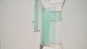 Um corredor estreito com uma porta que dá para um banheiro com box verde.