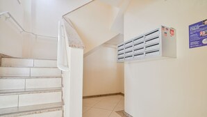 Uma escadaria leva a um patamar com um armário fixado na parede e um cartaz.