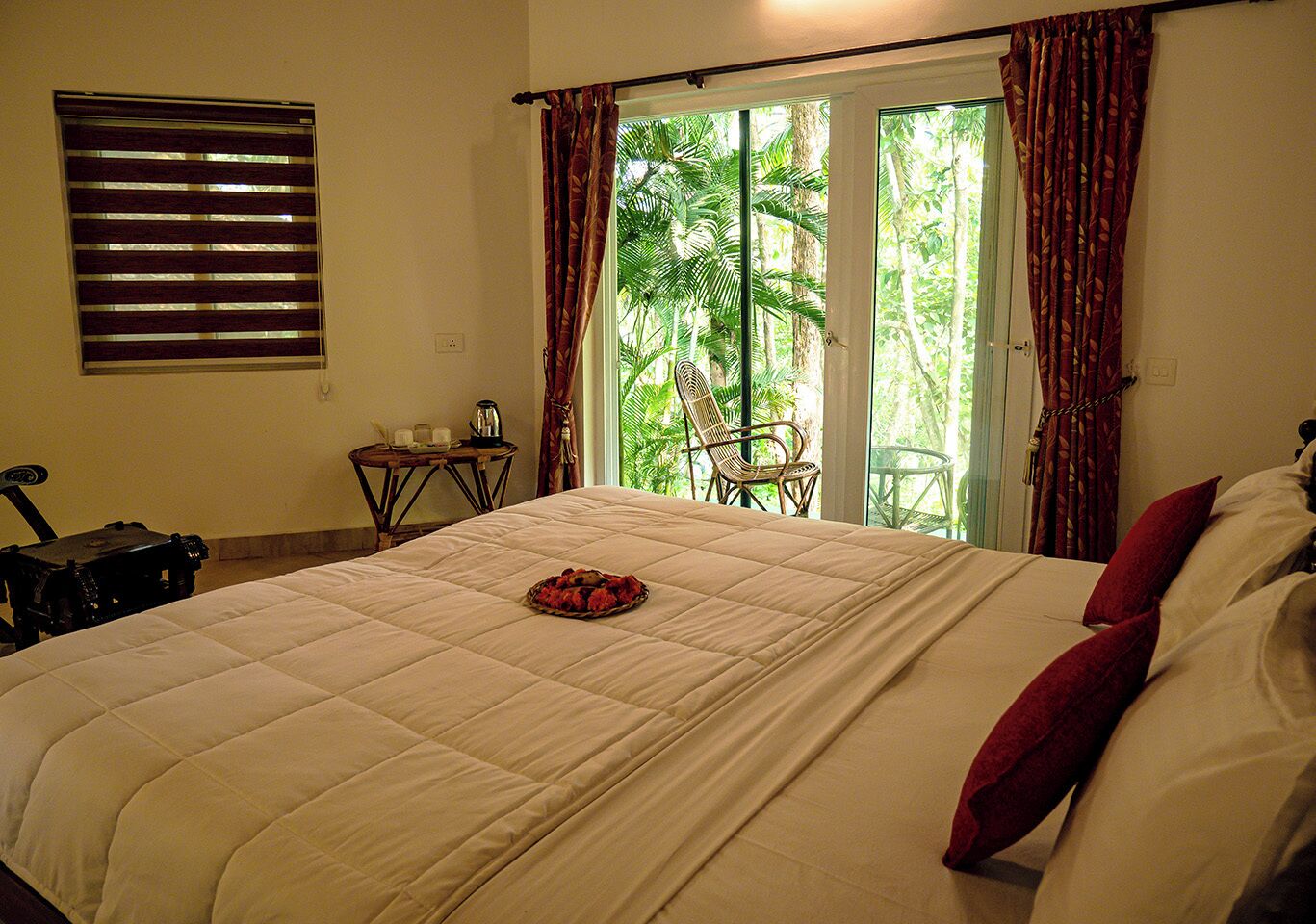 A bedroom with a bed, a chair, a small table, and a window with curtains.