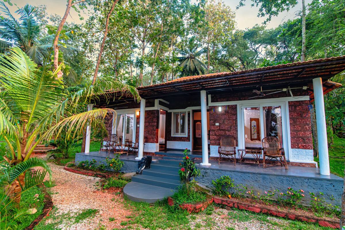 A building with a covered porch, outdoor seating, and a garden path.