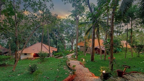 Un resort tropical con varias edificaciones tipo bungalow, un sendero de grava y exuberante vegetación.
