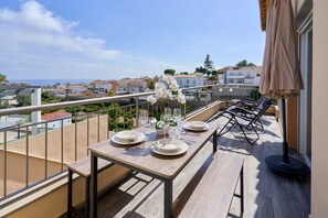 A balcony with a table set for dining, overlooking a coastal town. - Villa 'Oasis D Sol I-Private Pool' with Sea Views, Wi-Fi and Air Conditioning (Urbanización Cerro Garbancito)