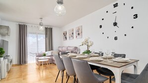 A modern dining area with a large wall clock, grey chairs, and a dining table set for four. - Villa 'Oasis D Sol I-Private Pool' with Sea Views, Wi-Fi and Air Conditioning (Urbanización Cerro Garbancito)