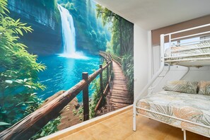 Een kamer met een stapelbed, een muurschildering van een waterval en een houten pad.