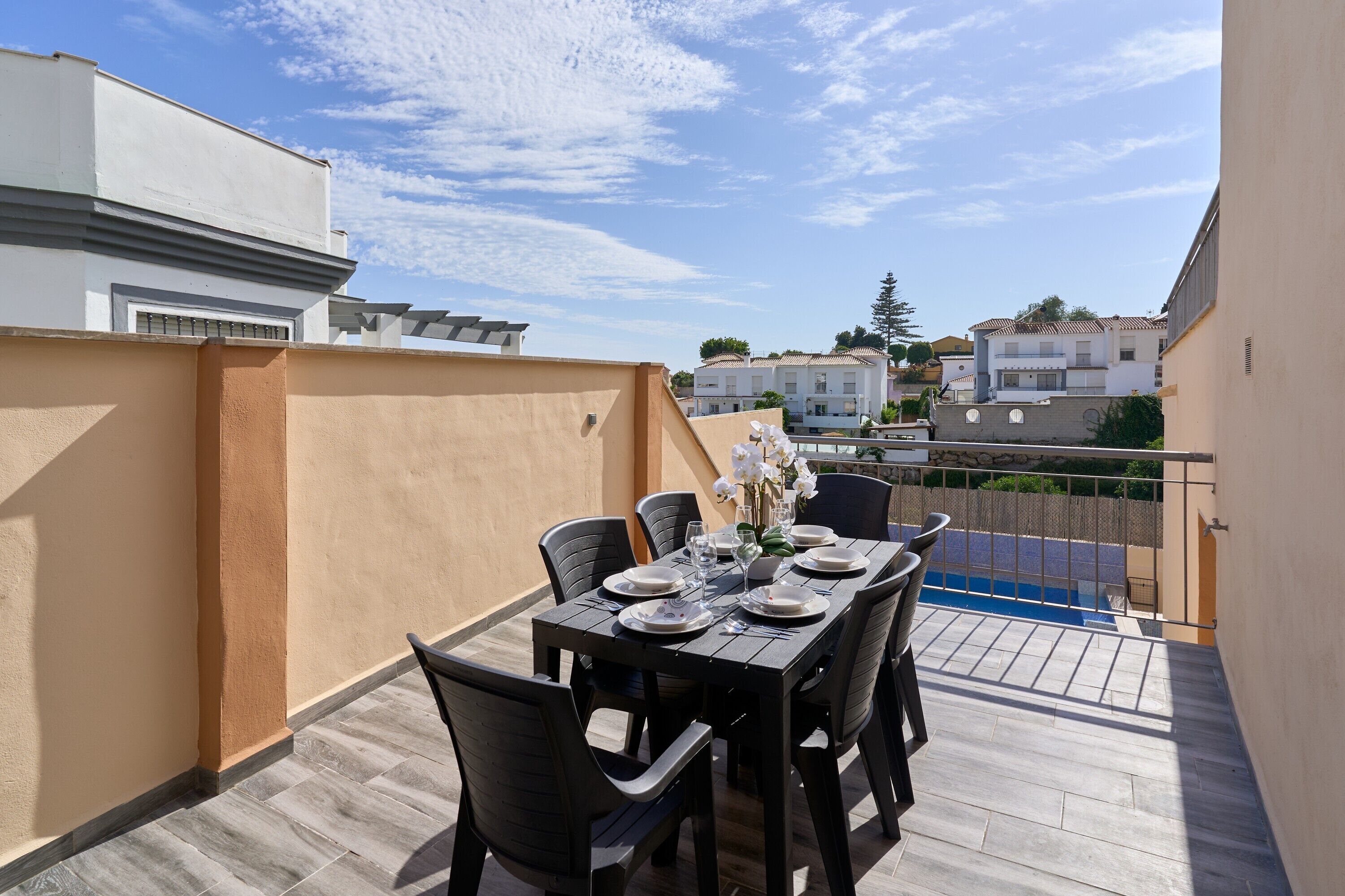 Un balcón con mesa para cuatro, sillas y vista a edificios cercanos.