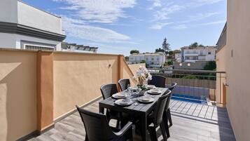 Un balcón con mesa para cuatro, sillas y vista a edificios cercanos.