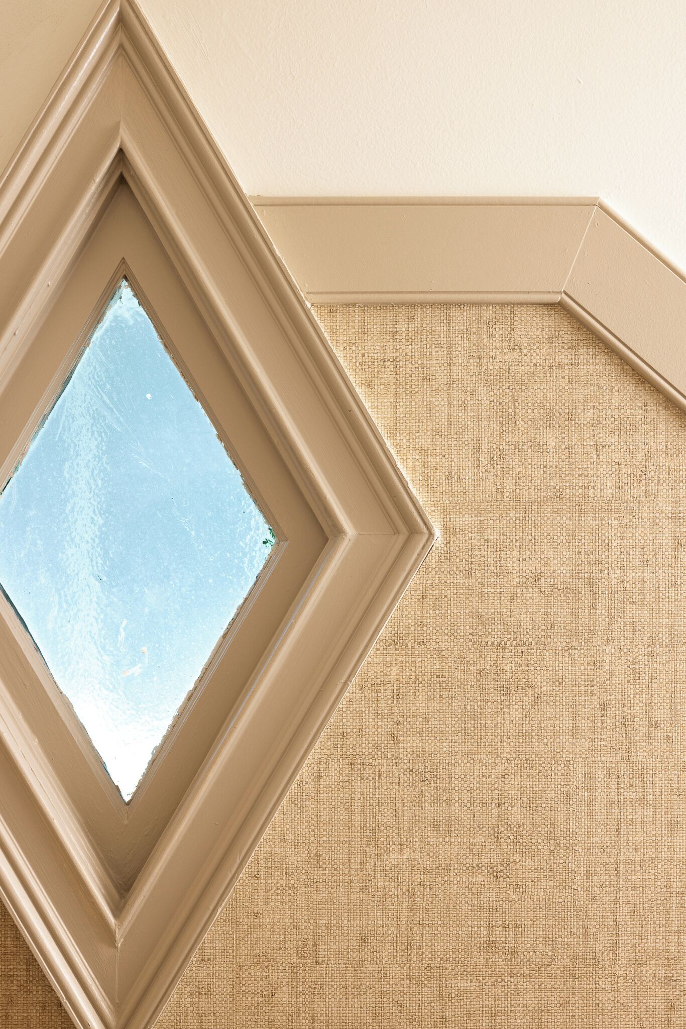 A corner of a room with a textured beige wall and a framed window.