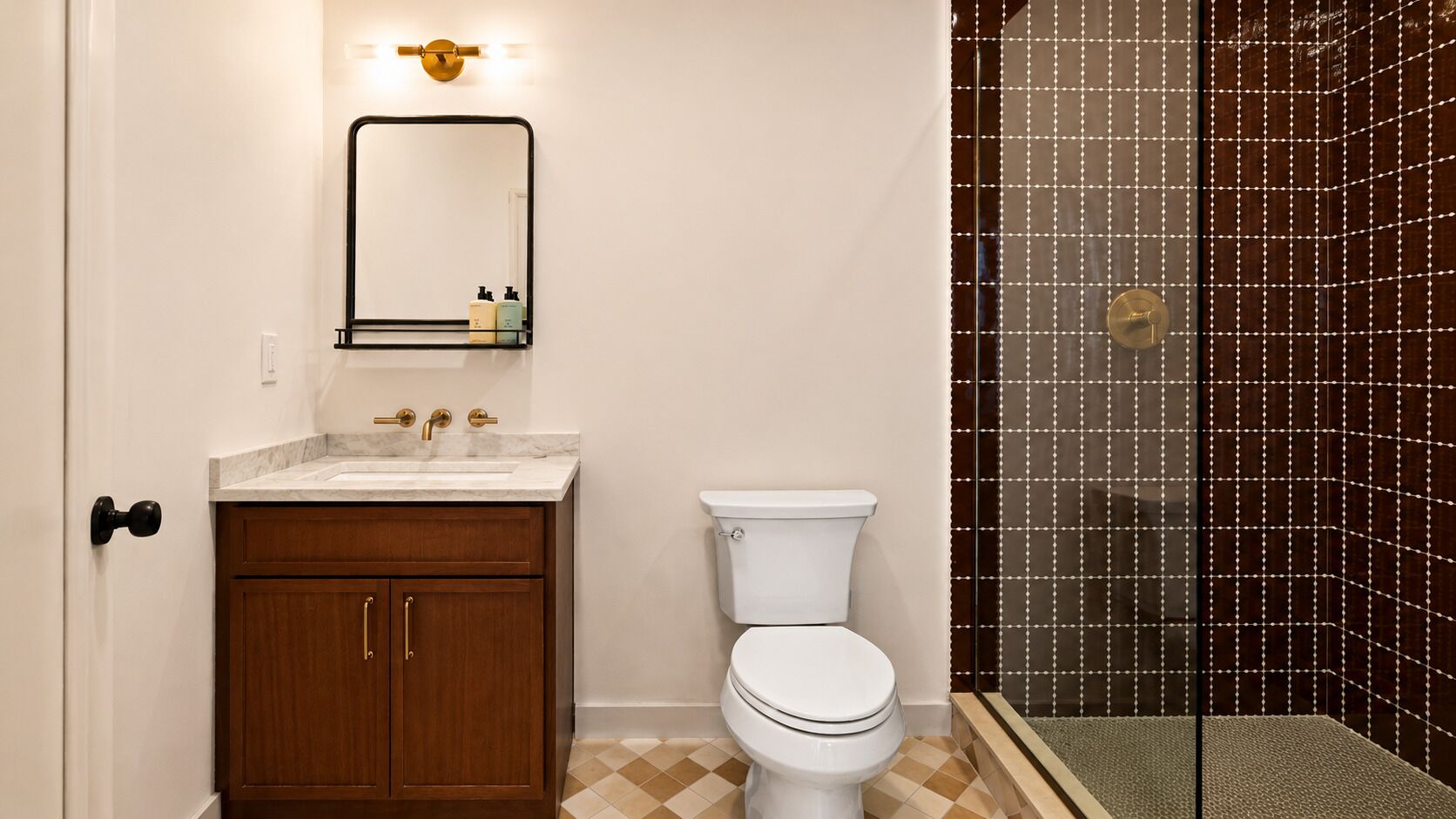 A bathroom with a toilet, sink, and mirror.
