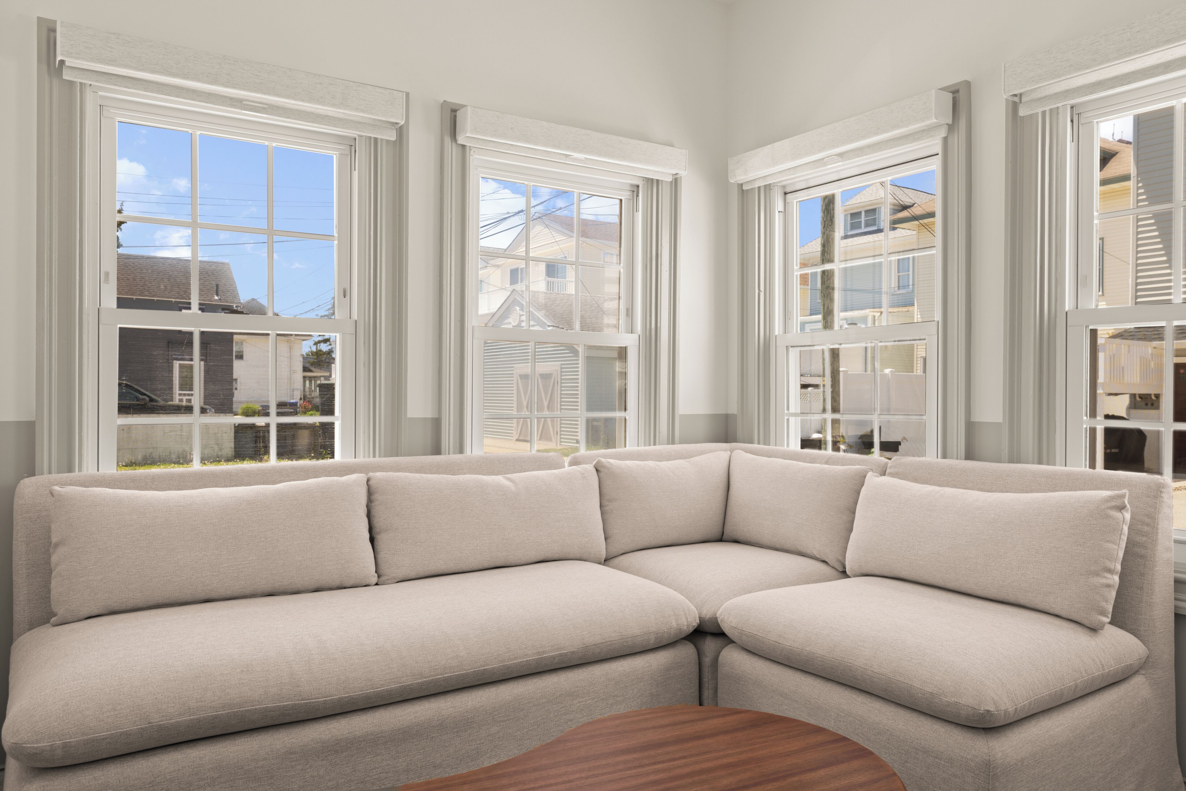 Ein Eckmodulsofa in einem Zimmer mit großen Fenstern und Blick auf angrenzende Häuser.