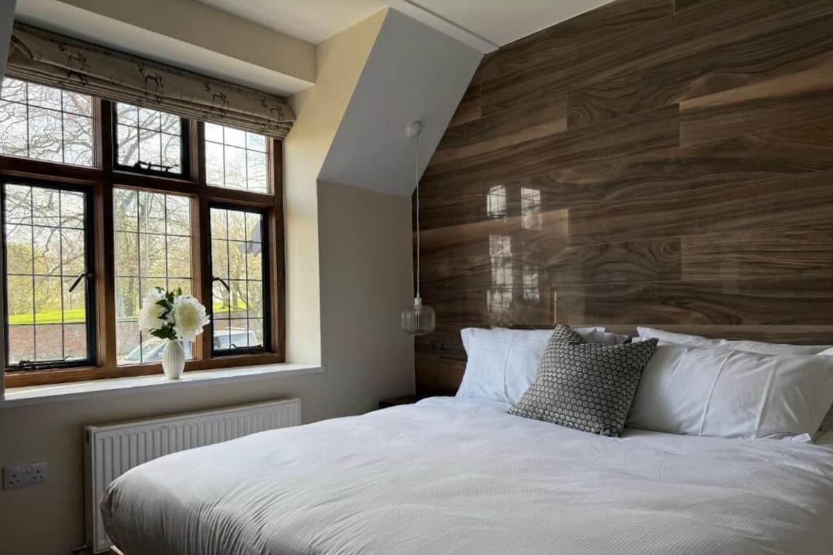A bedroom with a large bed, a window with a view, and a wooden headboard.