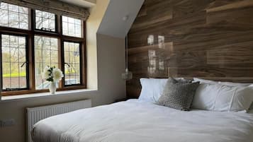 Un dormitorio con una cama grande, una ventana con vistas y un cabecero de madera.