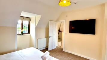 A bedroom with a bed, a TV mounted on the wall, a window with a view, and a ceiling light fixture.