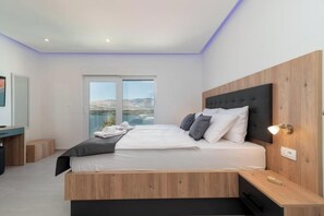 Ein modernes Schlafzimmer mit einem großen Bett, einem Schreibtisch und Blick ins Freie.