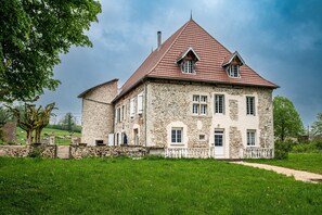 Un bâtiment en pierre avec un toit rouge, de nombreuses fenêtres et un mur en pierre.