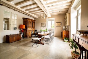Une pièce spacieuse avec un plafond en bois, une table à manger avec des chaises, une grande armoire et une plante en pot.