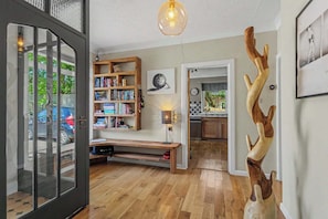 Ein modernes Interieur mit einer Holzbücherwand, einer einzigartigen Geweihskulptur und einer durch einen offenen Durchgang einsehbarer Küche.