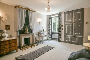 Un dormitorio con cama, cómoda, tocador y chimenea.