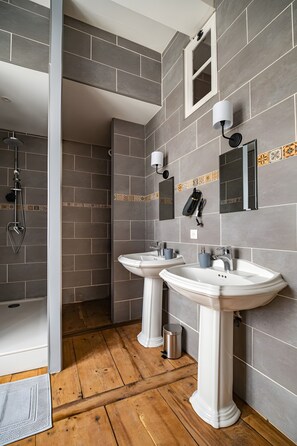Une salle de bain avec deux lavabos, une douche et un miroir.