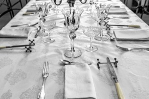 Een tafel gedekt met fijn porselein, bestek en kristallen glazen, wat wijst op een formele dineropstelling.