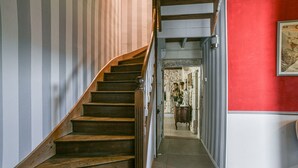 A staircase with wooden steps and a handrail, leading to a room with a red wall and a framed picture.