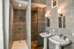 A bathroom with a shower, two sinks, and a mirror.