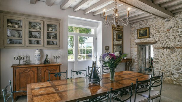 A dining room with a wooden table, chairs, a chandelier, and a stone wall. - Guest Room “Chambre du Parc”: Mountain View, Shared Terrace, Wi-Fi (Saint-Albin-de-Vaulserre)