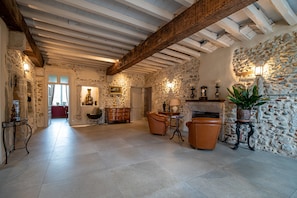 Una habitación con paredes de piedra, chimenea, muebles de cuero y viga de techo de madera.
