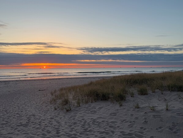 Ein Strand mit Dünen und einem Sonnenuntergang.