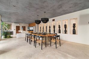 Ein Essbereich mit einem langen Tisch, schwarzen Stühlen und einer modernen Decke.