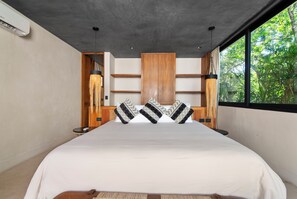 Ein modernes Schlafzimmer mit einem großen Bett, einem Holzkopfende und Blick auf Grünflächen.