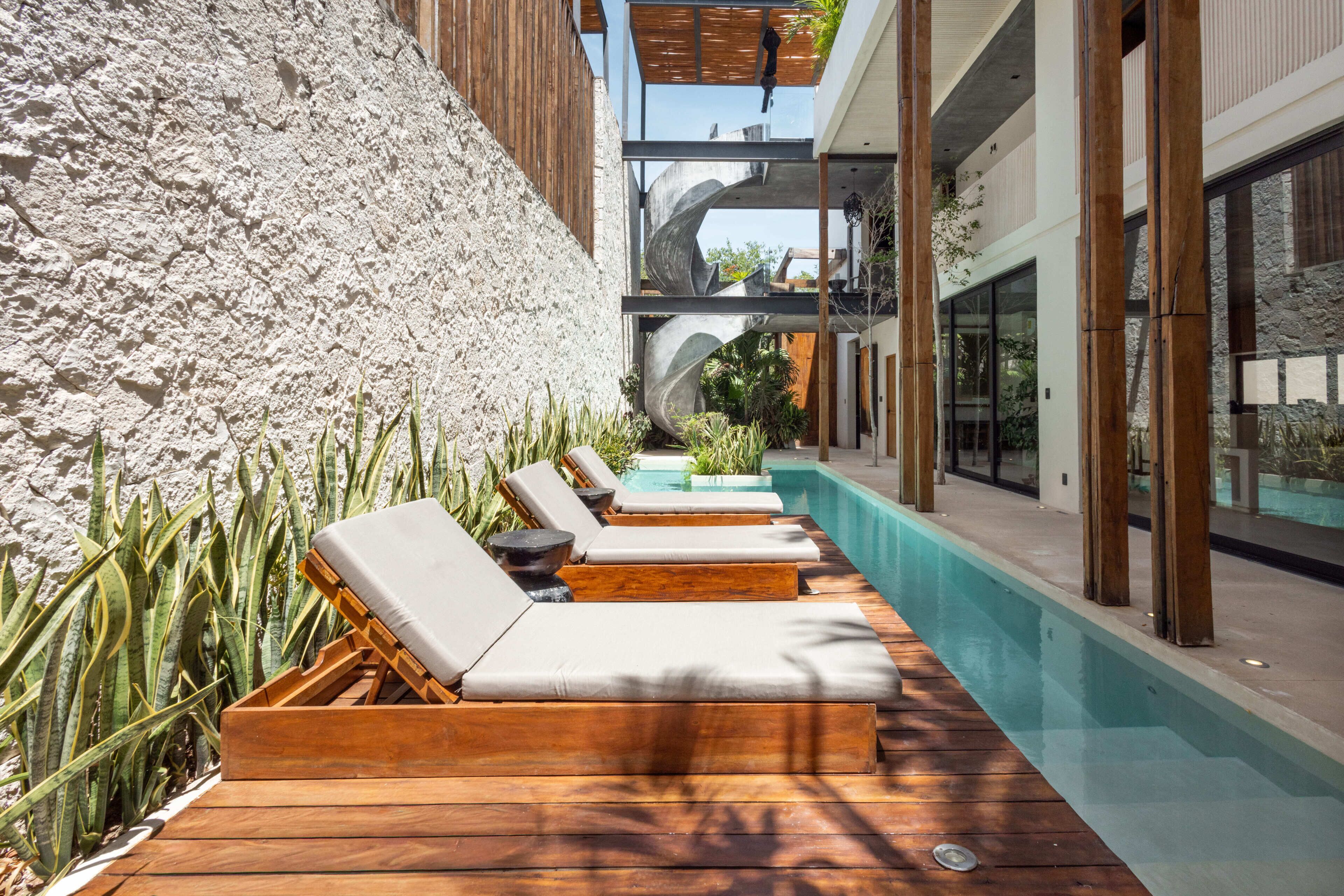 A poolside area with wooden loungers, a stone wall, and a clear view of the pool.