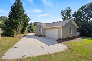 A single-story house with a garage, a driveway, and a well-maintained lawn. - Pebble Creek Cottage (Taylors)