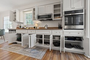 A modern kitchen with white cabinetry, a stainless steel oven, and a built-in microwave.