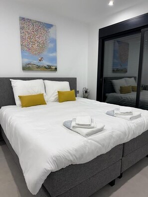 Una habitación de hotel moderna con una cama grande, un vidrio y un cuadro en la pared.