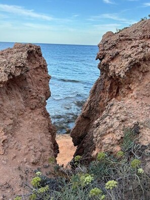 Eine Küstenlandschaft mit einer steilen Klippe und einem schmalen Durchgang zum Meer.