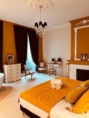 Un dormitorio con cama, cómoda, escritorio, silla, chimenea y candelabro.