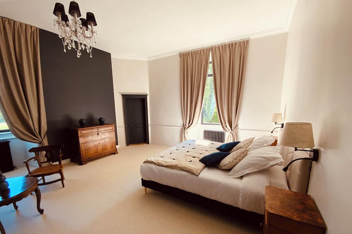 Ein Schlafzimmer mit Bett, Kommode, Stuhl und einer Chandelier.