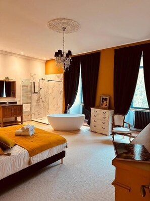 Un dormitorio moderno con una cama grande, una bañera independiente, un tocador y un candelabro.