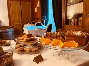 Un bufé de desayuno con diversos pasteles, galletas y fruta.