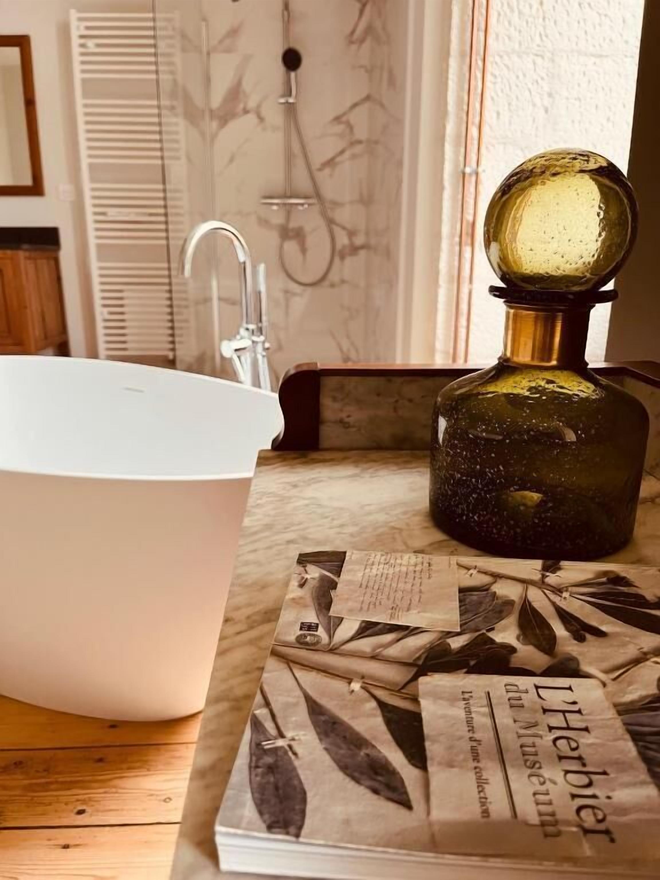 A bathroom with a white sink, a glass bottle, and a magazine on the counter.