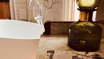 A bathroom with a white sink, a glass bottle, and a magazine on the counter.