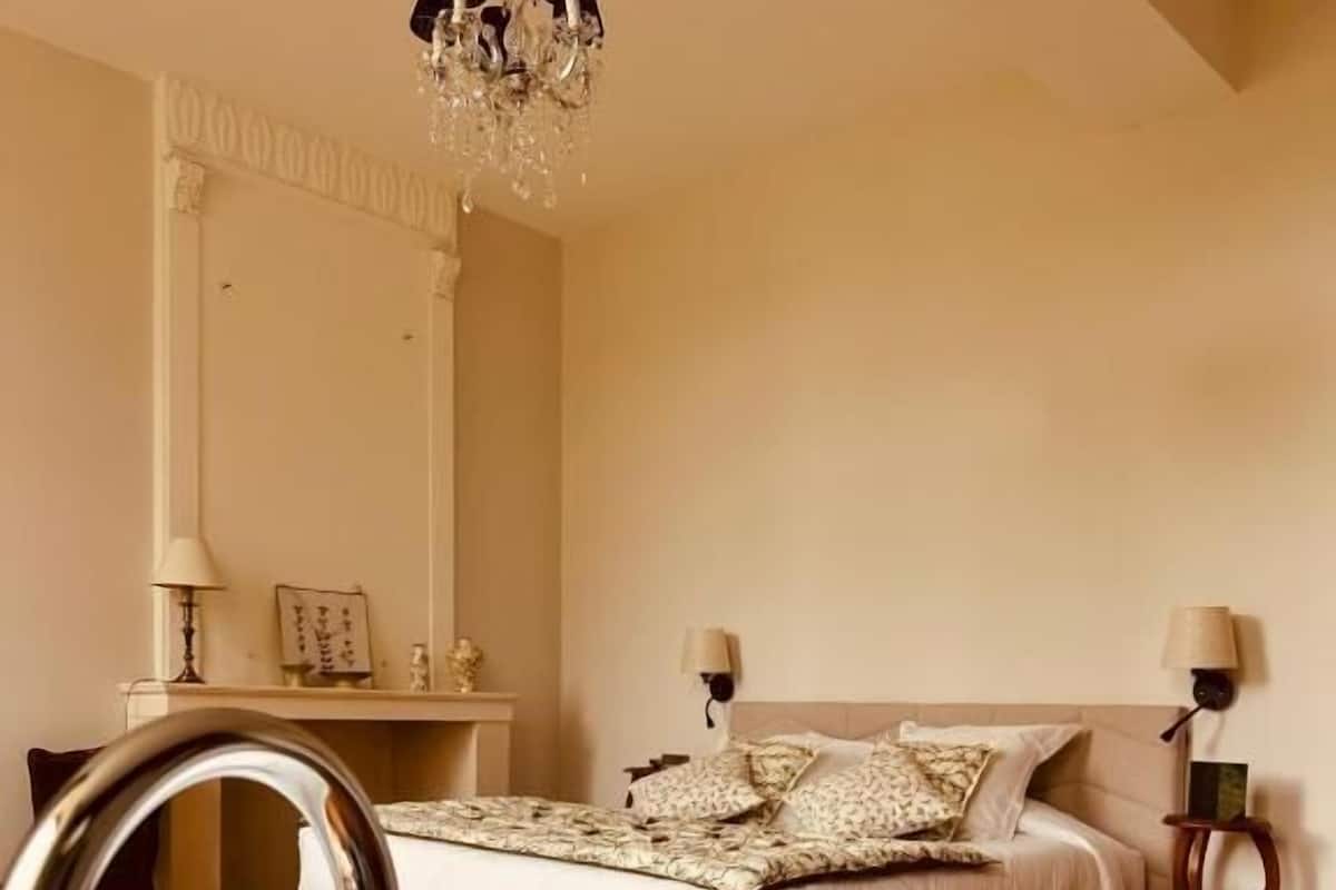 Ein Schlafzimmer mit einer großen Badewanne, einem Bett mit Kissen, einer Chandelier und einem Spiegel.