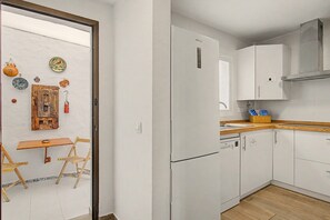 Une cuisine avec des armoires blanches, un four encastré et un plan de travail en bois.