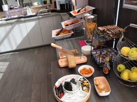 A buffet setup with various food items, a knife, and a fruit basket.