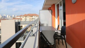 A balcony with a table and chairs, a city view, and a red wall.