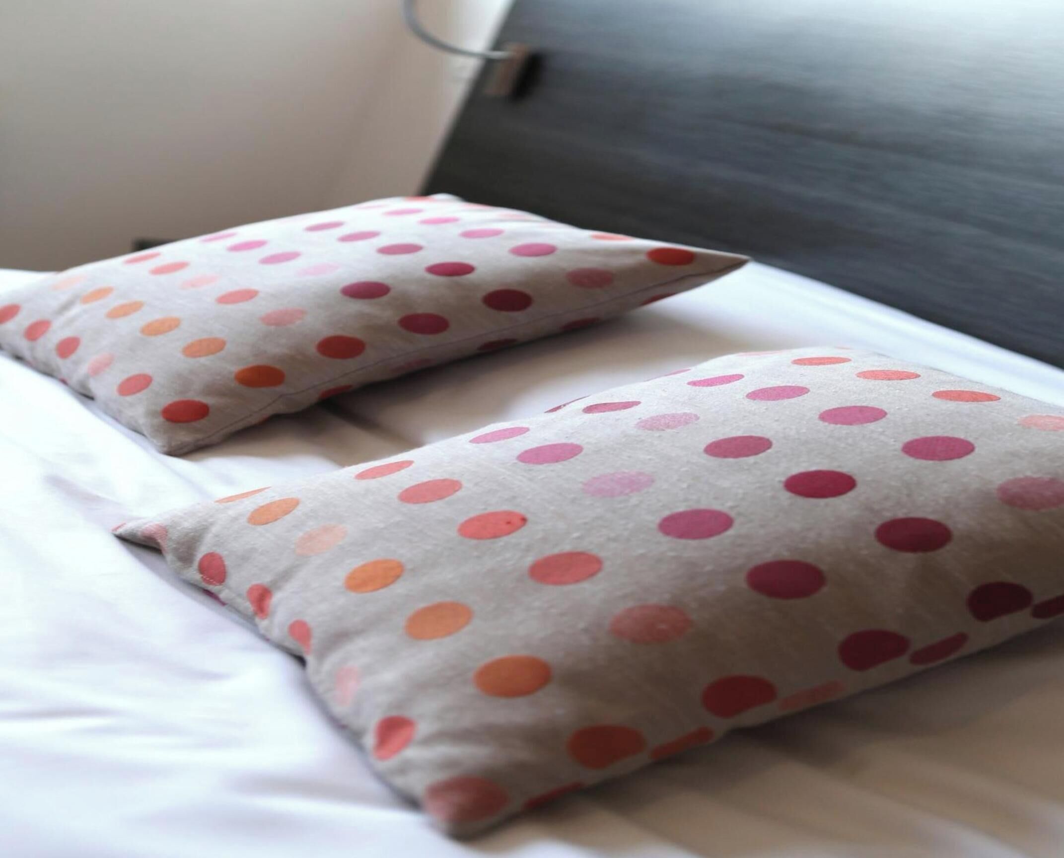 Two pillows with a polka dot pattern on a bed.