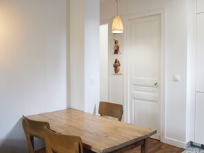 Ein Essbereich mit Holztisch und Stühlen, einer Pendelleuchte und einer weißen Tür mit einem kleinen Kunstwerk darüber.