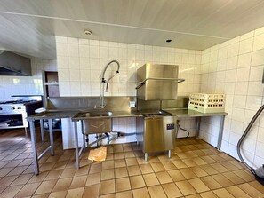 Et professionelt køkken med stålemmer, flisebeklædt bagvæg og gulv.