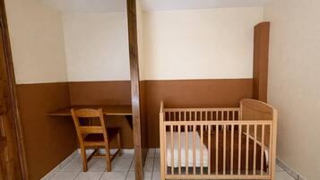A room with a wooden desk, a chair, and a wooden crib.